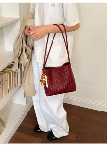 Classic burgundy woven shoulder bag featuring a wooden bead tassel in a lifestyle setting