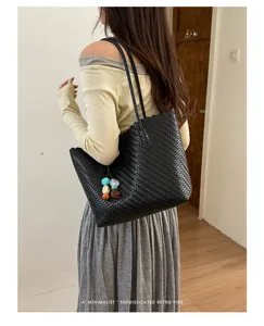 Primer plano de bolso tote de cuero trenzado negro con cuentas de colores en modelo