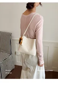 Detailed shot of a French-style white woven shoulder bag worn by a model in lifestyle setting