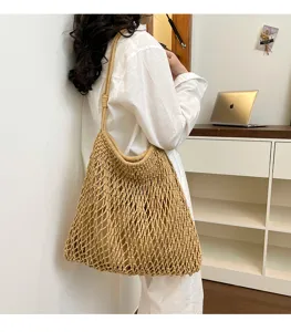 Bolso tote de malla tejida beige llevado por una modelo en un ambiente de interior