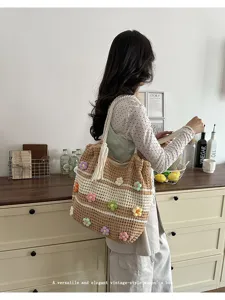 Detail of a handmade brown knit tote bag featuring colorful 3D floral appliqués and tassels