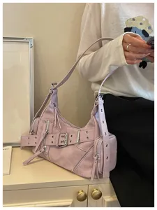 Dettaglio di una borsa biker lilla con borchie, fibbia e accenti di cerniera