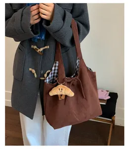 Detail of a retro brown suede tote bag with a cute croissant charm and checkered lining