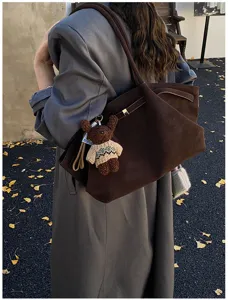 Grand sac cabas vintage marron avec breloque ours porté à l'épaule en automne.