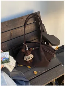 Gros plan du sac cabas vintage en daim marron avec un charm d'ours
