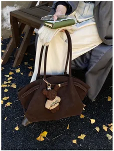 Détail lifestyle d'un grand sac cabas rétro marron orné d'un pendentif ours mignon.