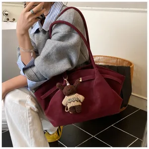 Vue détaillée d'un sac cabas bordeaux vintage avec un charm ours mignon pour le bureau.