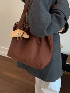 Retro brown large capacity suede tote bag with croissant charm shown on model in a gray coat