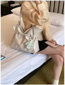 Sac cabas blanc cassé avec ceinture décorative et breloque lapin dans un décor de vie