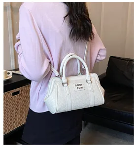 Vue détaillée d'un sac à main blanc texturé porté par un mannequin dans un décor intérieur