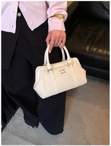Vue détaillée d'un sac à main crème gaufré avec plaque de logo métallique élégante