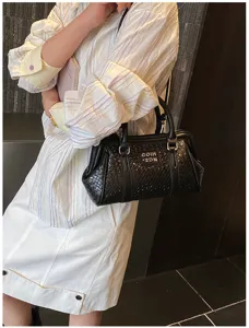 Gros plan d'un sac à main noir à texture tissée porté par un mannequin en tenue