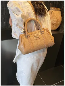 Sac à main beige texturé porté par un mannequin avec logo métallique élégant