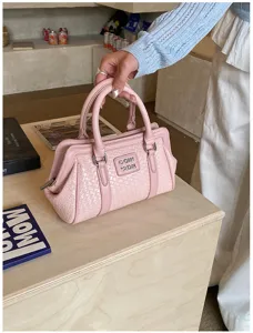 Gros plan d'un sac à main rose gaufré et tissé avec des poignées élégantes et un logo