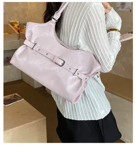 Model met een zachtroze leren draagtas met een decoratieve gesp aan de riem