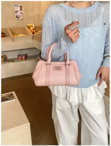 Vue détaillée d'un sac à main rose à texture tissée avec poignées supérieures et logo