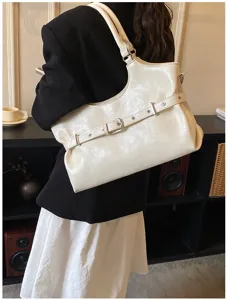 Detailopname van een witte glanzende lakleren draagtas met een riem met gesp-detailband