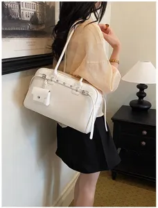 Elegant white soft leather underarm bag shown on model in a stylish indoor setting