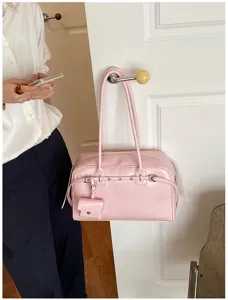 Detailed close-up of a pink soft leather underarm bag hanging on a white door handle.