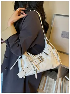 Borsa a spalla bianca con borchie indossata da una modella con un cappotto scuro.