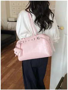 Elegant pink soft leather shoulder bag with stud details worn by a model in a white shirt