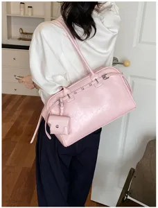Trendy pink soft leather shoulder bag with mini pouch worn by a model in a bright room