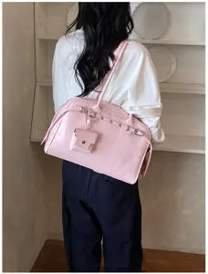 Detail of a pink soft leather shoulder bag worn by a model in a minimalist setting
