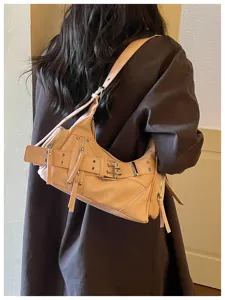 Vista dettagliata di una borsa a tracolla beige stile biker con rivetti e fibbie