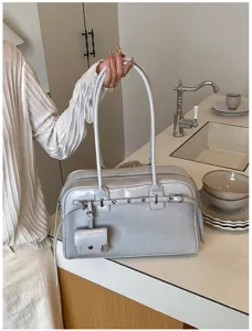 Chic grey minimalist soft leather shoulder bag with buckle details in a lifestyle setting