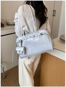 Rear view of minimalist gray leather underarm bag worn over a pleated white blouse