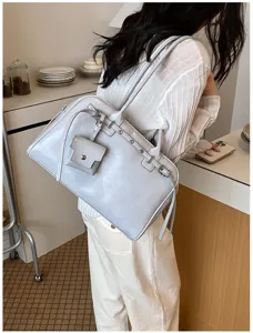 Soft grey faux leather shoulder bag worn by model in a minimalist cafe setting