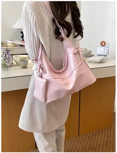 Detail of pink soft leather hobo bag with matching pouch on model in cafe setting