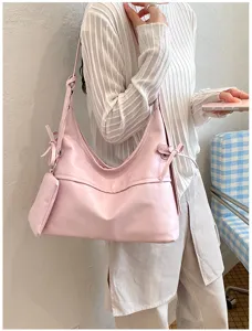 Elegant pink soft leather hobo bag with bow accents and a matching accessory pouch
