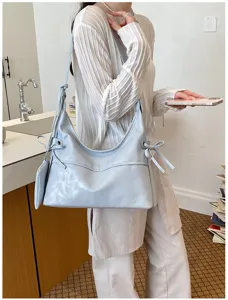 Light blue soft leather hobo bag with bow details carried by a model in kitchen