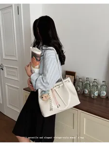 Mannequin portant un sac cabas vintage crème avec ceinture dans un décor de vie