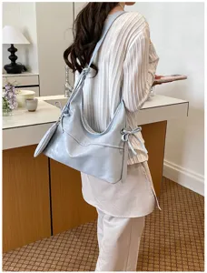 Stylish light blue soft leather hobo bag with bow detail worn by a model in a cafe