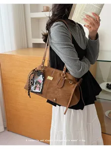 Klassische braune Umhängetasche mit Doppelträgern, getragen von einem eleganten Model.
