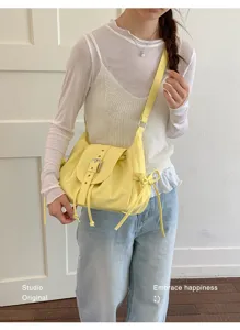 Detail of yellow nylon shoulder crossbody bag with belt buckle flap on person.