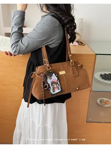 Elegante braune Vintage-Umhängetasche aus Leder mit einem schicken Cartoon-Anhänger.
