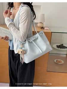 Détail d'un sac cabas élégant en cuir bleu clair de style vintage tenu par un mannequin.