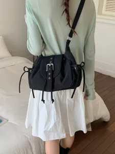 Stylish black nylon commuter crossbody bag featuring a belt buckle flap and side drawstrings