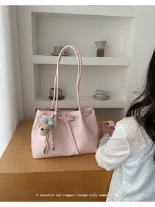 Sac cabas vintage rose élégant avec design de ceinture et breloque ours sur table