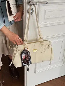 Klassische beige Unterarmtasche für Damen, hängend an einem weißen Türgriff im Raum