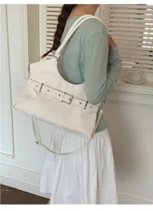 Detailopname van een minimalistische witte tote tas met gesp gedragen als schoudertas