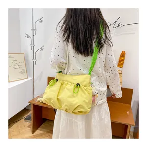 Bright yellow canvas drawstring messenger bag worn by a model in a trendy casual setting