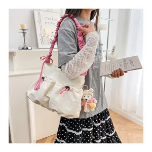Model wearing a white canvas tote bag with pink drawstring and cute bear charm.