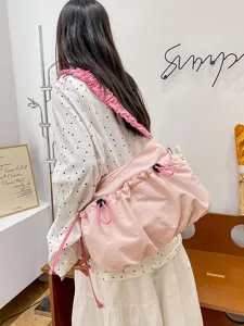 Stylish pink utilitarian drawstring canvas tote bag with ruffled strap on model