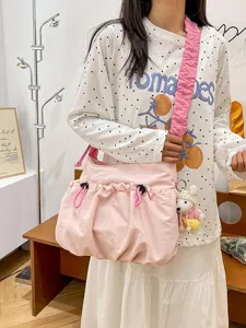 Pink utilitarian canvas shoulder bag with drawstring design and ruffled strap.