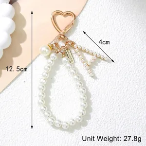 Detailed macro view of pearl letter A keychain with heart-shaped gold clip and size