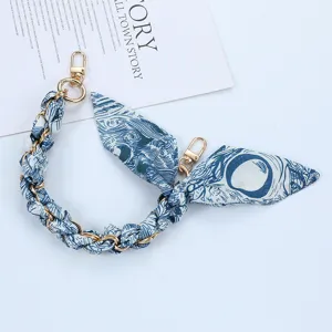 Detailed macro shot of the elegant woven blue scarf and gold chain phone strap accessory